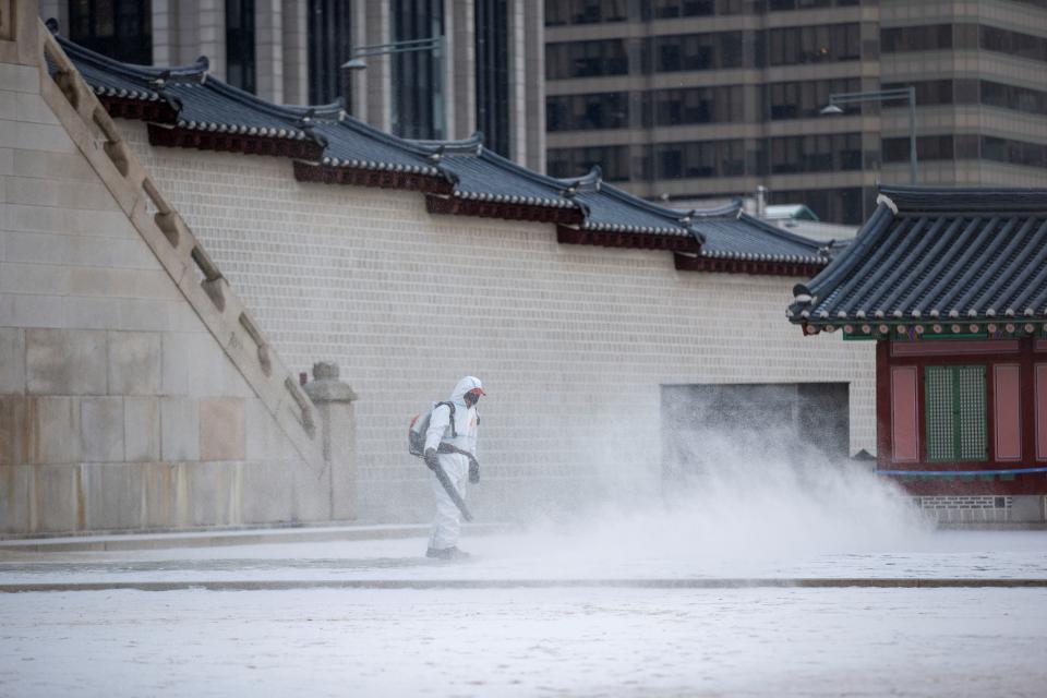 A worker clears snow inside the Gyeongbokgung Palace in Seoul, South Korea, Jan. 17, 2022. (Photo by Wang Yiliang/Xinhua via Getty Images)