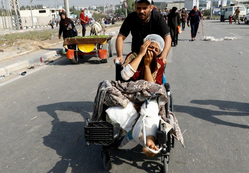 A Palestinian woman, who was being treated at al-Shifa hospital, moves south to avoid the Israeli airstrikes (Reuters)