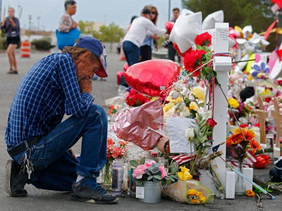 Antonio Basco kneels at a memorial for his wife Margie Reckard and other victims of the El Paso shooting (EPA)