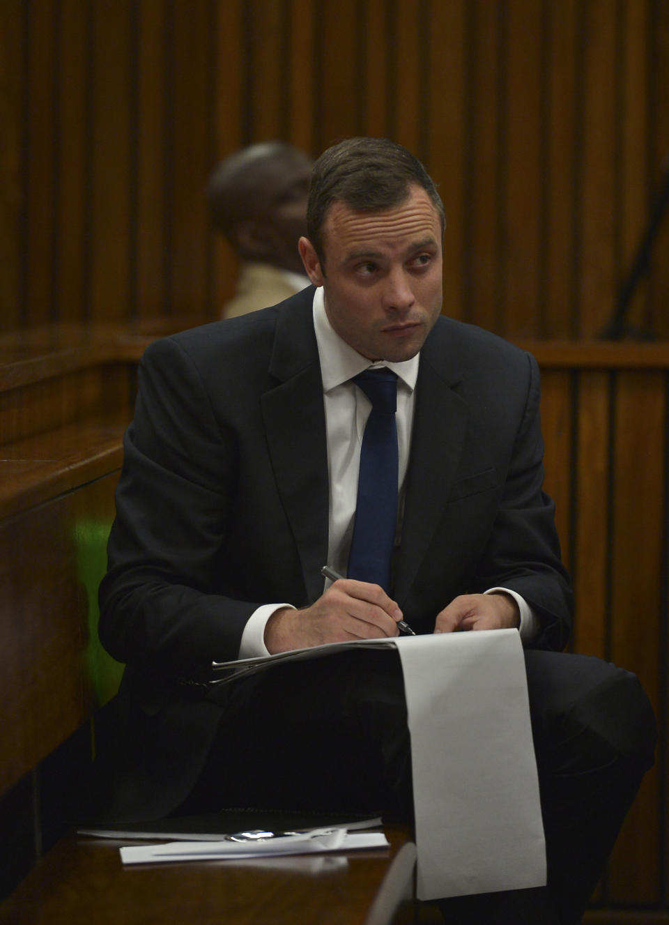 Oscar Pistorius makes notes as he sits in the dock listening to cross questioning about the events surrounding the shooting death of his girlfriend Reeva Steenkamp, in court during the second week of his trial in Pretoria, South Africa, Wednesday, March 12, 2014. Pistorius is charged with the shooting death of Steenkamp, on Valentines Day in 2013. (AP Photo/Alexander Joe, Pool)