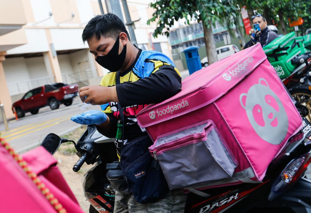 A Foodpanda rider is pictured sanitising his hands before making a delivery in George Town March 24, 2020. — File picture by Sayuti Zainudin