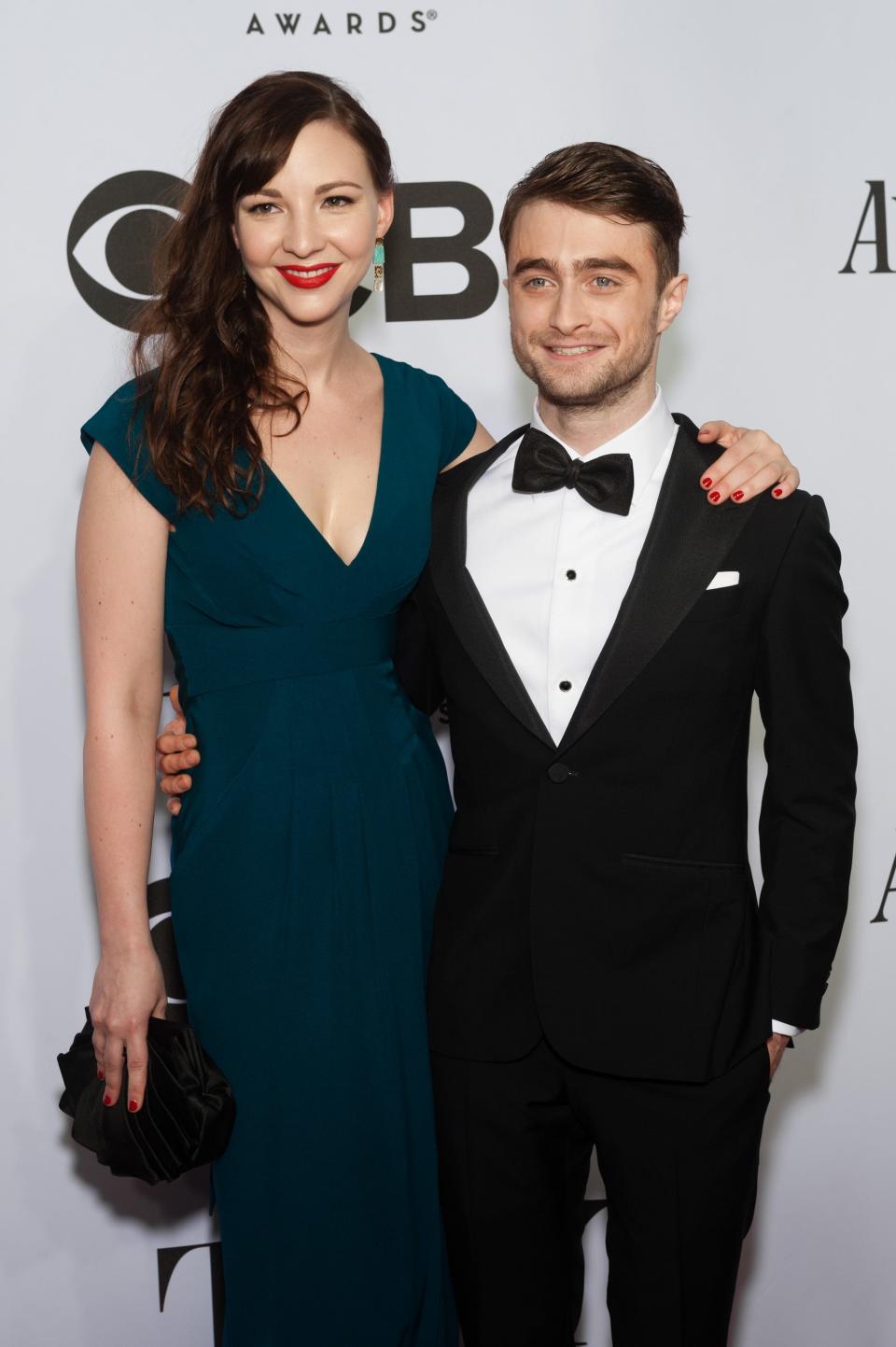 Erin Darke in a dark green gown standing taller than Daniel Radcliffe in a tuxedo.
