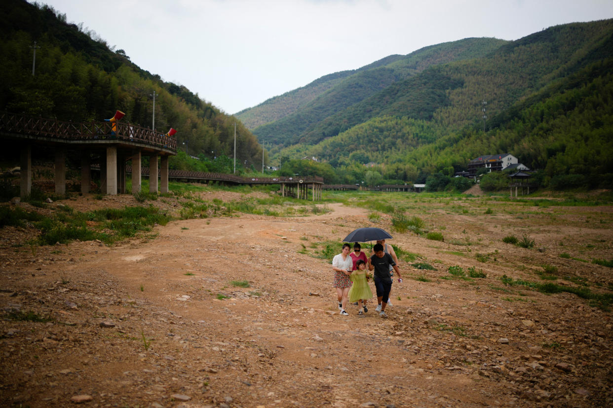 People walk on a dried-up bed of a reservoir, amid hot temperatures, while many regions from southwest to east of the country along the Yangtze river have been experiencing weeks of record-breaking heatwave in Changxing, Zhejiang province, China, August 20, 2022. REUTERS/Aly Song