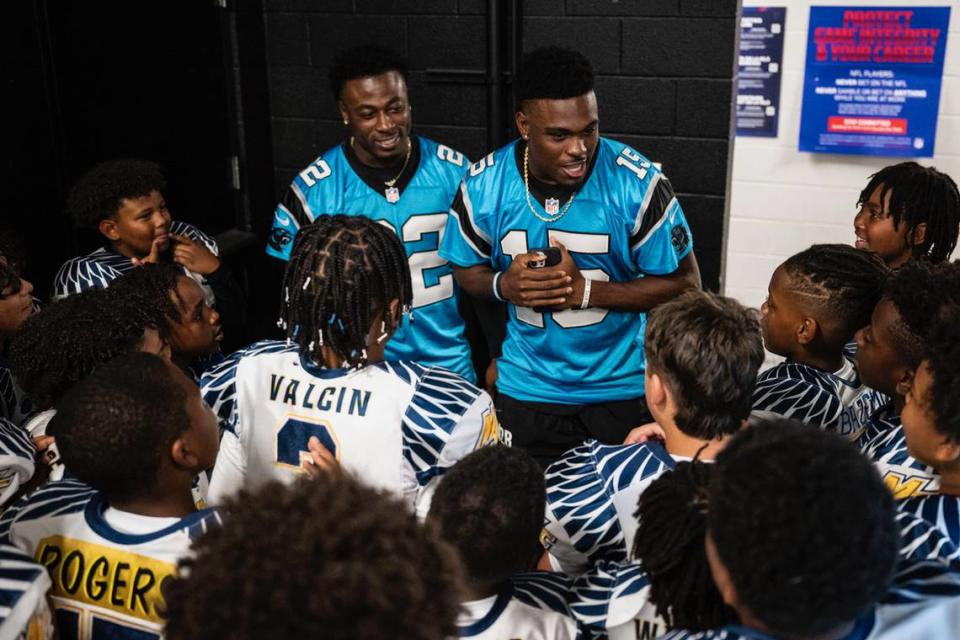 Jammie Robinson, left, and Jonathan Mingo, right, deliver a pump-up speech to the Chargers before they play in their youth football league championship on Monday, Oct. 30, 2023, in Bank of America Stadium.