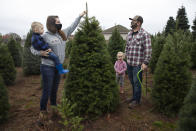 Josh and Jessica Ferrara shop for Christmas trees with son Jayce, 1 year and Jade, 3 years, at Sunnyview Christmas Tree farm on Saturday, Nov. 21, 2020 in Salem, Ore. It's early in the season, but both wholesale tree farmers and small cut-your-own lots are reporting strong demand, with many opening well before Thanksgiving. (AP Photo/Paula Bronstein)
