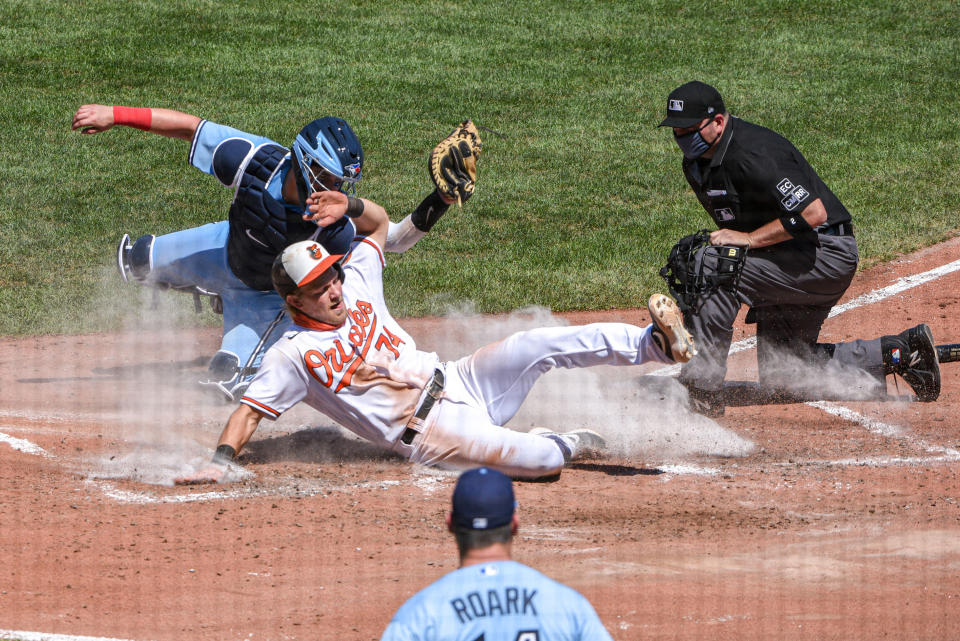 Toronto Blue Jays catcher Reese McGuire, left, tags the Baltimore Orioles' Pat Valaika out at the plate, with umpire Dan Bellino, right, making the call in the fourth inning at Oriole Park at Camden Yards in Baltimore on Wednesday, Aug. 19, 2020. The Blue Jays won, 5-2. (Ulysses Munoz/Baltimore Sun/Tribune News Service via Getty Images)