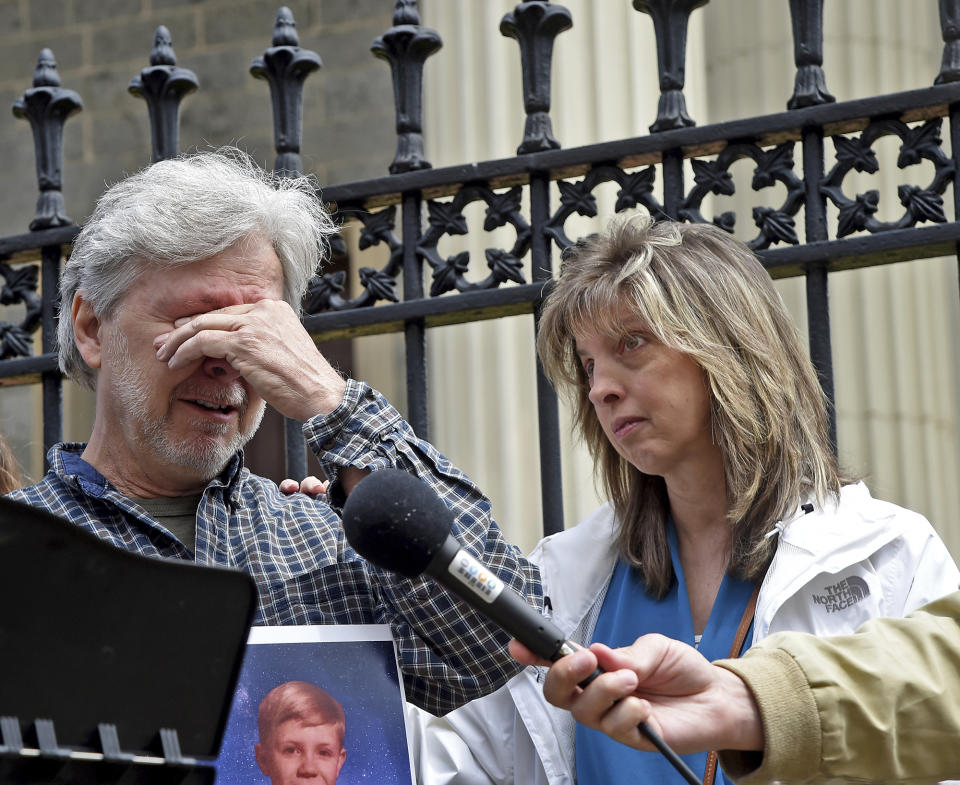 Victim Marc Floto of Westminster, standing with his wife, Melissa, right, gets emotional as he describes his experience since being abused by a priest during his childhood, during a news conference, Tuesday, May 9, 2023, in Baltimore. He is holding a photograph of himself as a child. After Maryland lawmakers recently passed legislation eliminating the statute of limitations for child sex abuse lawsuits amid increased scrutiny of the Archdiocese of Baltimore, civil rights attorney Ben Crump announced a series of civil claims Tuesday he plans to bring on behalf of victims. (Barbara Haddock Taylor/The Baltimore Sun via AP)