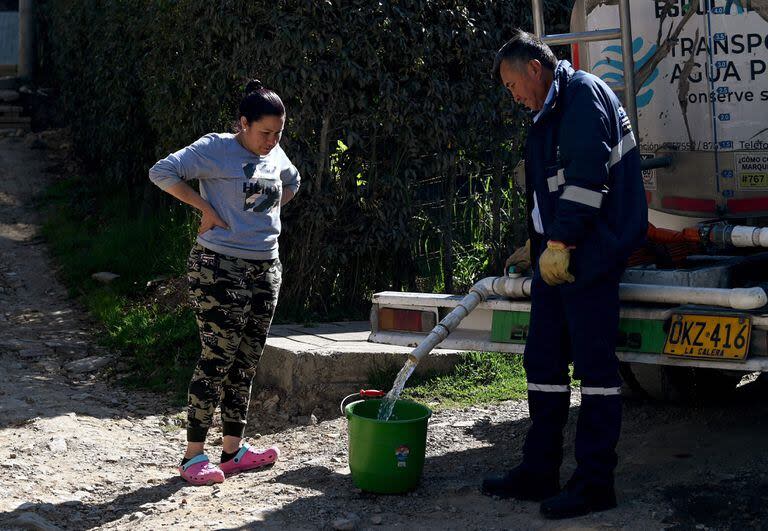 Una mujer junta agua potable de un camión cisterna en La Calera, cerca de Bogotá, el 10 de abril de 2024. 