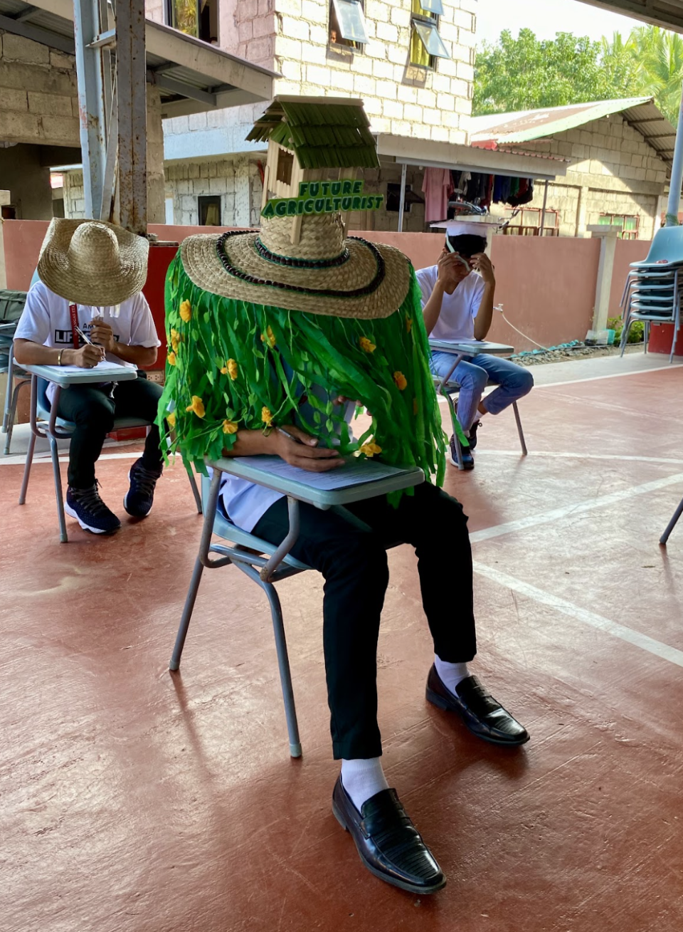 Person seated wearing a large hat with "Future Agriculturist" text