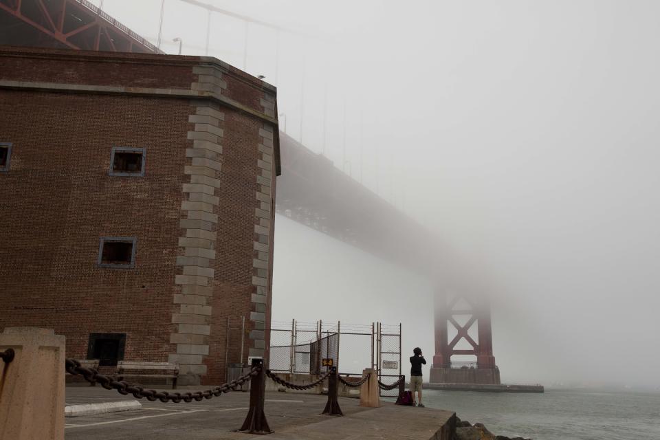 In this photo taken Thursday, Sept. 27, 2012, a man stands beside Fort Point and looks out at the fog-covered Golden Gate Bridge in San Francisco. San Francisco has a long history as a favorite site for filmmakers and the movie buffs who want to see the spots where their favorite scenes took place, from Fort Point under the Golden Gate Bridge where Jimmy Stewart saved Kim Novak in "Vertigo" to the steps of City Hall, where Sean Penn gave an impassioned speech in "Milk," to Alcatraz, stage for Clint Eastwood and many others. (AP Photo/Eric Risberg)