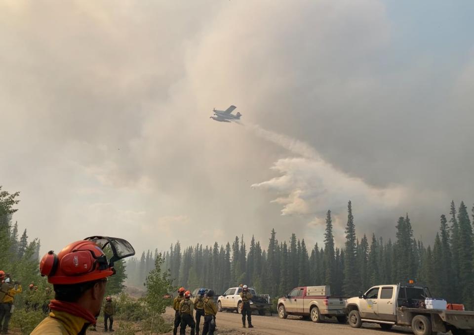 Firefighters respond to a wildfire in Fort Good Hope, N.W.T. On June 28, a pilot flying a helicopter to help with fire suppression died in a crash.  