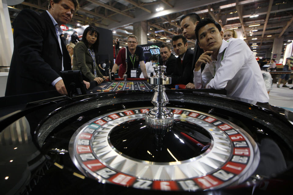 FILE - Staff members of the Gaming Expo Asia sit at a roulette table during the trade show and conference for the Asian gaming market in Macau on Tuesday, May 22, 2012. (AP Photo/Kin Cheung)
