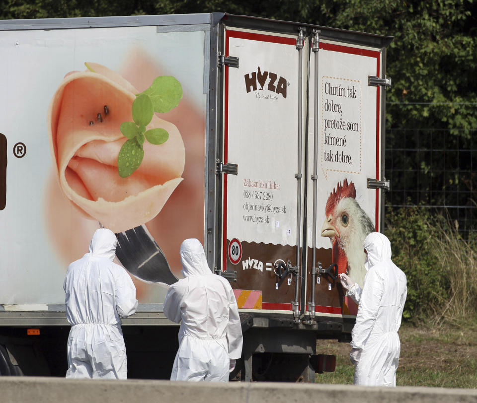 FILE - In this Thursday, Aug. 27, 2015 file photo, investigators stand near an abandoned truck on the shoulder of Highway A4 near Parndorf, Austria, south of Vienna. A Hungarian court has extended the prison sentences of four human traffickers convicted last year for their roles in a 2015 in which 71 migrants suffocated to death in the back of a refrigerated truck found on a highway in Austria. (AP Photo/Ronald Zak, file)