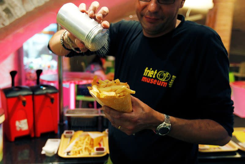 FILE PHOTO: A cook sprinkles salt on fries at a cafe in the Frietmuseum in Bruges