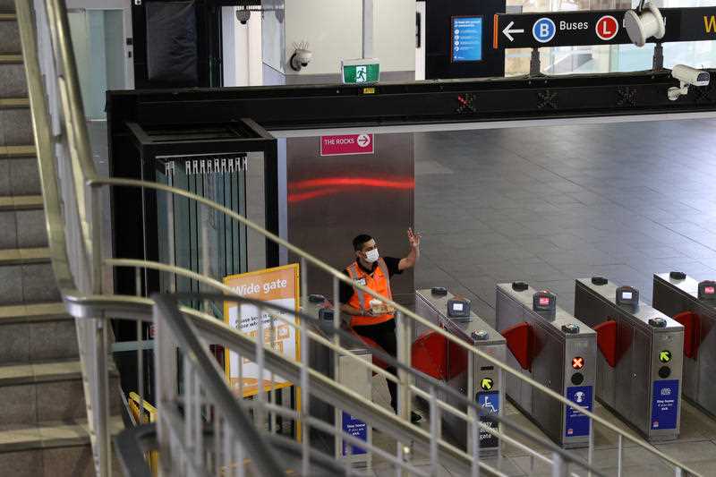 A masked worker gestures to a colleague at the Circular Quay train station in Sydney.