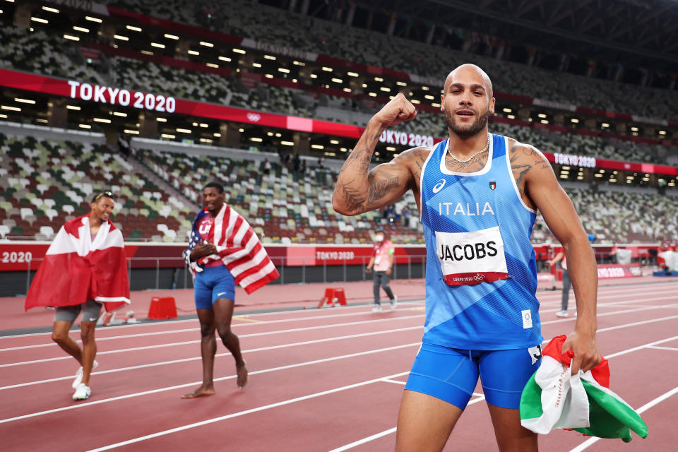 Italy's Lamont Marcell Jacobs celebrates after winning the men's 100m final, as USA's silver medallist Fred Kerley (C) and Canada's bronze medallist Andre De Grasse look on during the Tokyo 2020 Olympic Games at the Olympic Stadium in Tokyo on August 1, 2021. (Photo by Christian Petersen / POOL / AFP) (Photo by CHRISTIAN PETERSEN/POOL/AFP via Getty Images)