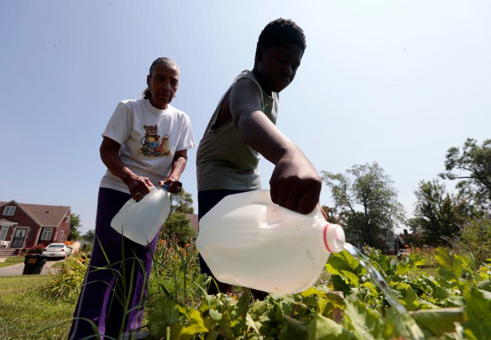 Wilma Rush, 81, left, watches as Laundry Kirksey, 12, of Detroit, adds water to plants at the Stoepel Community Garden on Stoepel Street in Detroit on Thursday, Aug. 3, 2023. The garden is part of Saturday's Neighborhoods Day in the city where volunteers show up to help beautify areas from community gardens to street cleanups.