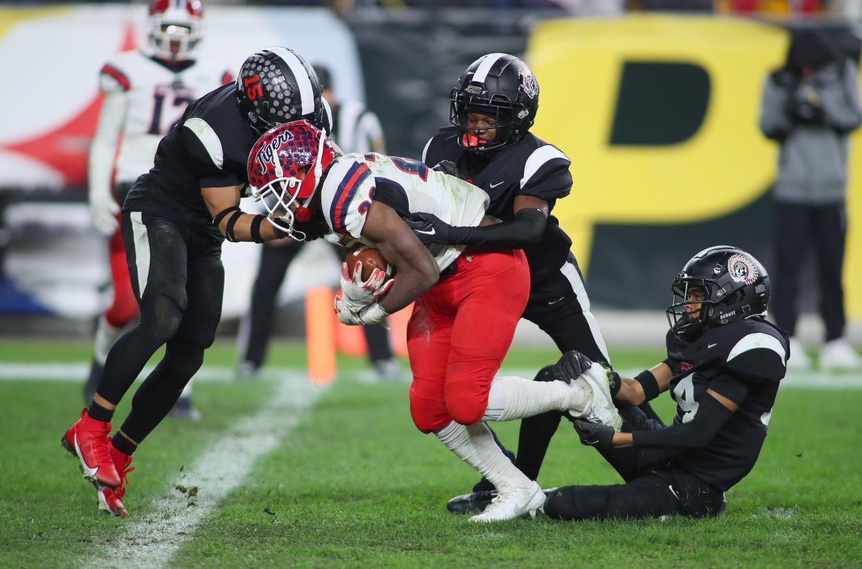 Aliquippa's QaLil Goode (14), Gavin Wilcox (13), and Arison Walker (15) attempt to hold back McKeesport's Kemon Spell (20) from scoring a touchdown during the second half of the WPIAL 4A Championship game Friday evening at Acrisure Stadium in Pittsburgh, PA.