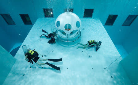 Belgians Florence Lutje Spelberg and Nicolas Mouchart dive next to "The Pearl", a spheric dining room placed 5 metres underwater in the NEMO33 diving center, one of the world's deepest pools (33 metre/36 yards) built to train professional divers, before enjoying a meal inside, in Brussels, Belgium January 30, 2017. Picture taken January 30, 2017 REUTERS/Yves Herman