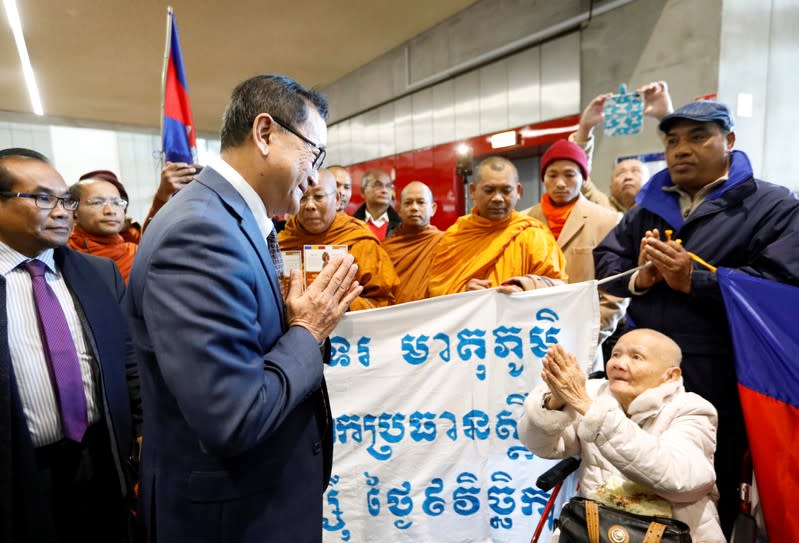 Cambodia's self-exiled opposition party founder Sam Rainsy, who has vowed to return to his home country, greets supporters after being prevented from checking-in for a flight from Paris to Bangkok at Roissy Airport in Paris