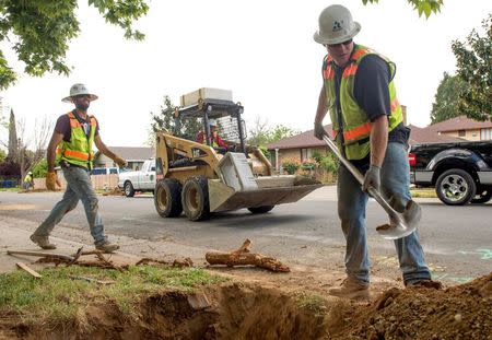Teichert Construction employees Ivan Gutierrez (L) and Ken Sanders install a water meter on 21st Street during the city's water meter retrofitting program in Sacramento, April 8, 2015. REUTERS/James Glover III