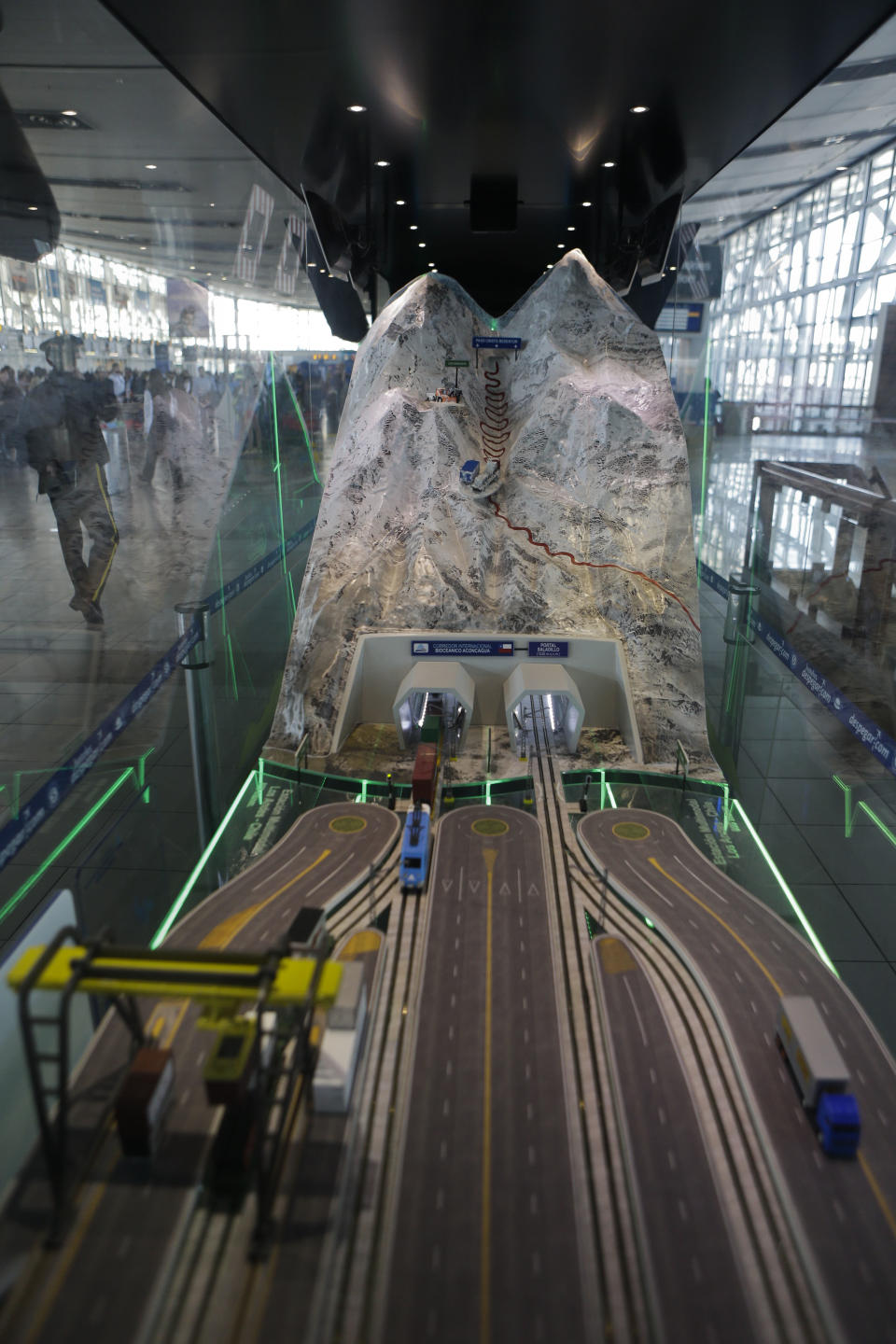 In this Sept. 12, 2012 photo taken through glass, a toy train emerges from a tunnel inside a miniature model of the proposed Aconcagua Bi-Oceanico Corridor, on display at the airport in Santiago, Chile. Two of South America's leading economies are neighbors but might as well be worlds apart, separated by a mountain wall with only one major land crossing that gets snowed in for up to two months every winter. An ambitious effort to build a private railway under Andean peaks aims to end the bottleneck. (AP Photo/Eduardo Di Baia)