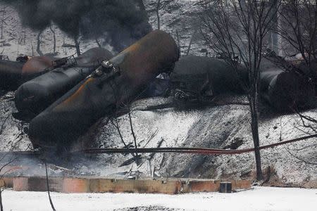 The charred remains of a house and a vehicle are shown below a derailed CSX Corp train in Mount Carbon, West Virginia, Tuesday, February 17, 2015. REUTERS/Marcus Constantino