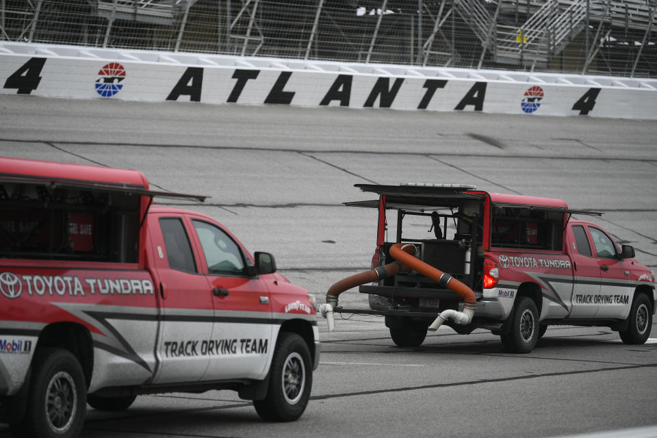 Trucks attempt to dry the track before practice and after qualifying was cancelled before a NASCAR XFINITY auto race at Atlanta Motor Speedway, Saturday, Feb. 23, 2019, in Hampton, Ga. (AP Photo/John Amis)