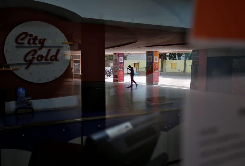 A worker cleans the premises of City Gold cinema after its reopenin in Ahmedabad