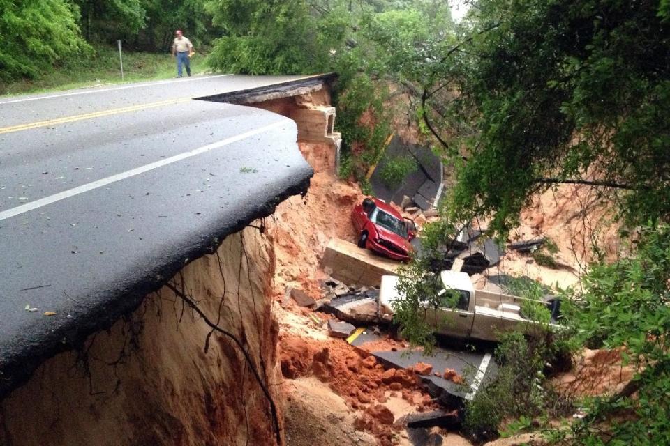 FILE -In this Wednesday April 30, 2014 file photo, a man walks near a portion of the Scenic Highway collapsed near Pensacola, Fla. Global warming is rapidly turning America into a stormy and dangerous place, with rising seas and disasters upending lives from flood-stricken Florida to the wildfire-ravaged West, according to a new U.S. federal scientific report released Tuesday, May 6, 2014. (AP Photo/Pensacola News Journal, Katie E. King, File)