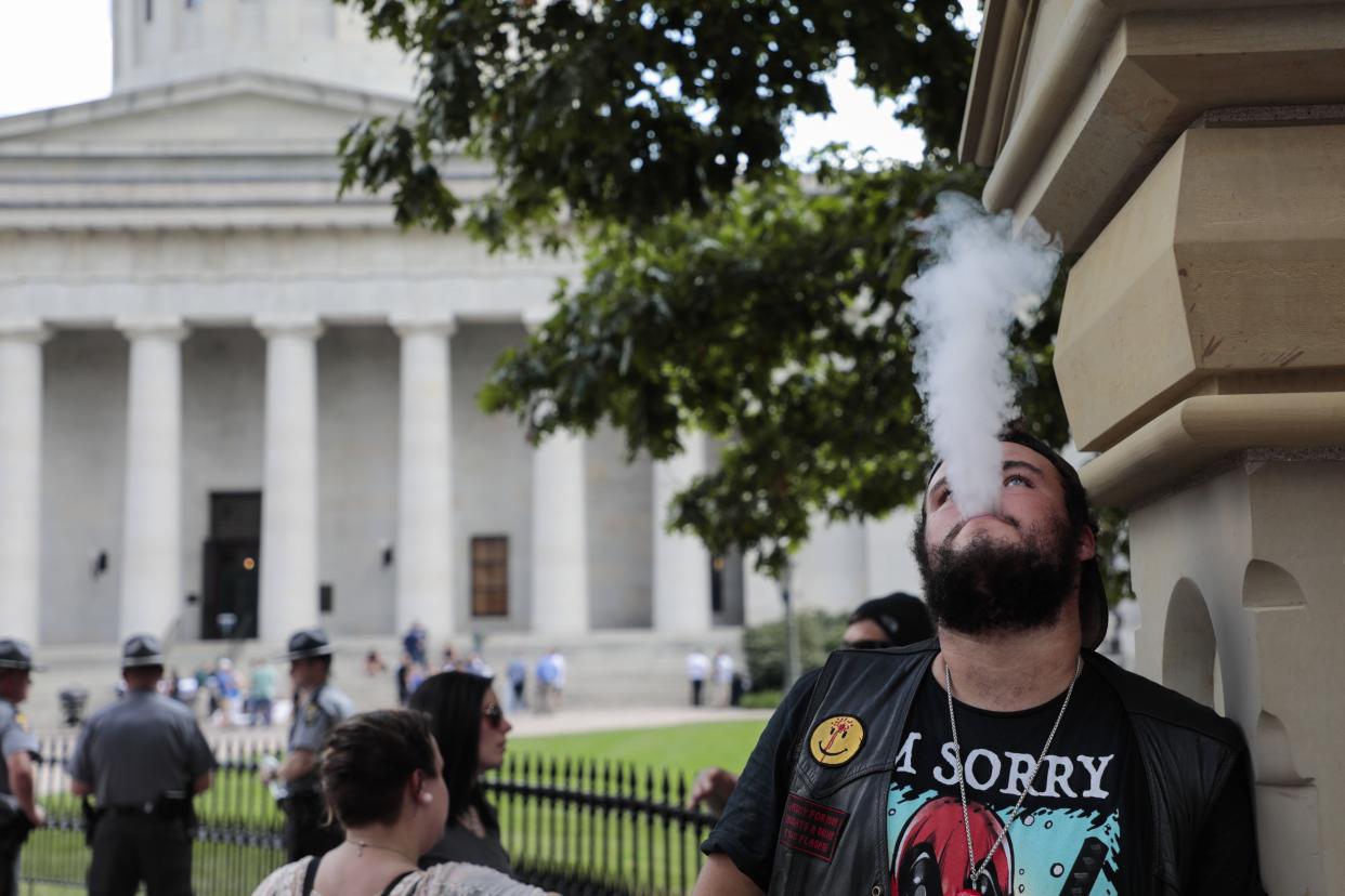 A man exhales while vaping following a vaping advocates rally on Oct. 1, 2019 at the Ohio Statehouse in Columbus. Free market conservatives in the Ohio Legislature are at odds with Gov. Mike DeWine over whether to ban the sale of flavored tobacco.