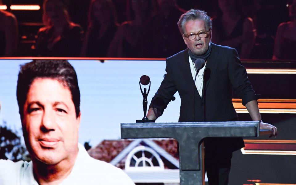 John Mellencamp, next to a photo of Allen Grubman, speaks onstage during the 37th Annual Rock & Roll Hall of Fame Induction Ceremony. (Photo: Valerie Macon/AFP via Getty Images)
