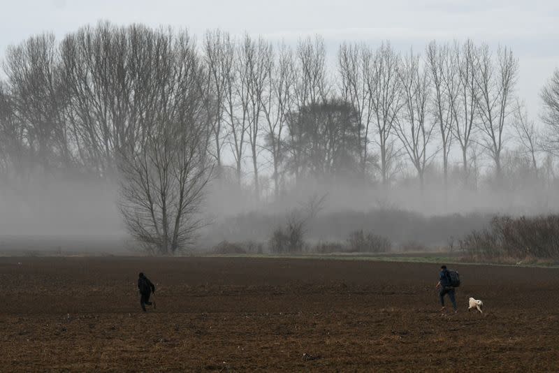 Two migrants who crossed the border from Turkey to Greece run through a field, near the town of Soufli, in the region of Evros