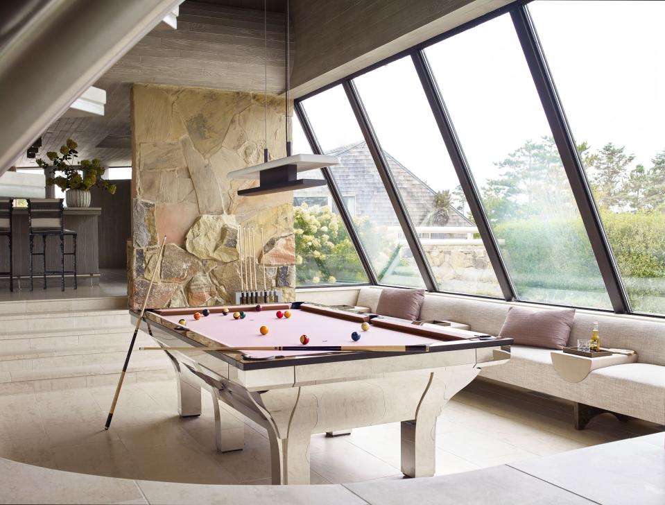 To complement the metal pool table, which came with the house, Moon commissioned a suspended lamp in darkened brass and marble from Liaigre, and designed a built-in banquette with leather armrests and cerused oak wooden trays.