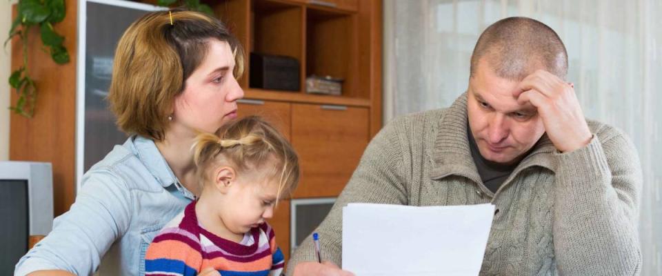 Serious couple with little girl counting budget at home