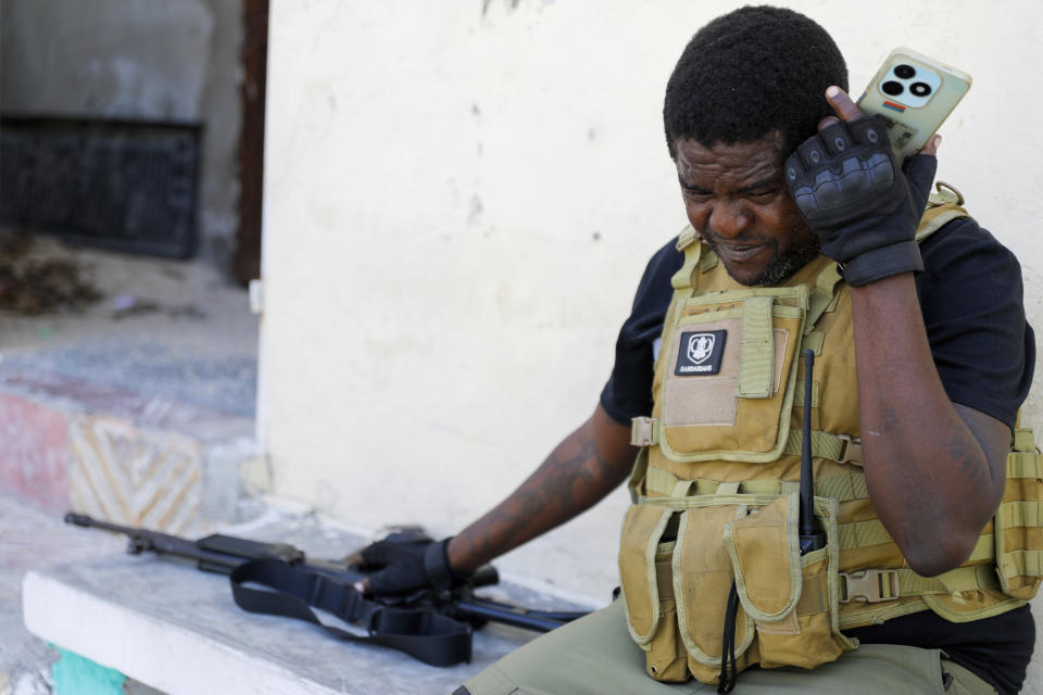 Barbecue, the leader of the "G9 and Family" gang, listens to his cell phone after addressing journalists in the Delmas 6 neighborhood of Port-au-Prince in Port-au-Prince, Haiti, Tuesday, March 5, 2024. Haiti's latest violence began with a direct challenge from Barbecue, a former elite police officer, who said he would target government ministers to prevent the prime minister's return and force his resignation. (AP Photo/Odelyn Joseph)