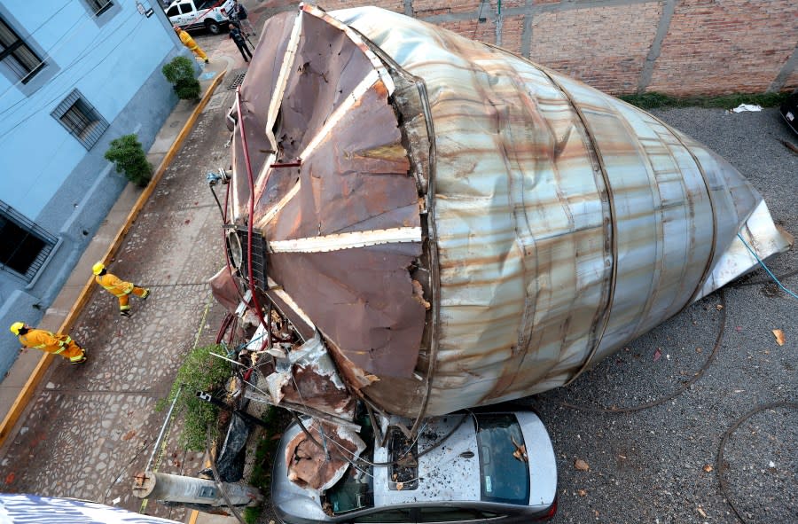 Aerial view of a car under a stainless steel container that blew about 200 metres in the air on July 23, 2024, after an explosion during maintenance work at the Jose Cuervo tequila factory in the Tequila municipality, Jalisco State, Mexico, taken on July 24, 2024. The explosion at the factory producing Jose Cuervo tequila killed at least five people on July 23, local authorities said. It was not yet known what caused the blast, with the company saying it happened during maintenance work. It impacted four containers with a capacity of 219,000 litres each, two of which collapsed, said Victor Hugo Roldan, state director of civil protection. (Photo by Ulises RUIZ / AFP) (Photo by ULISES RUIZ/AFP via Getty Images)