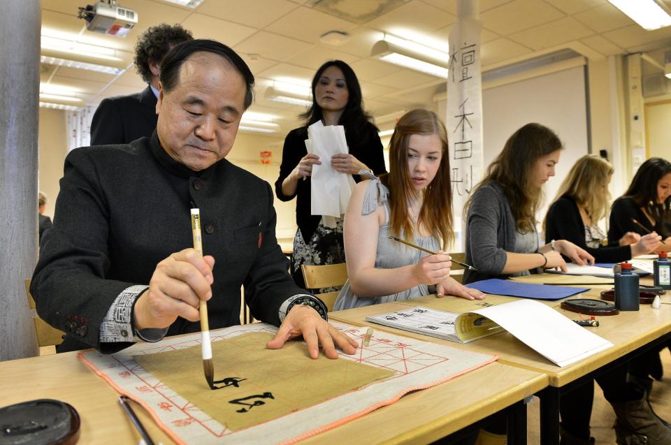 Winner of the Nobel Prize 2012 for literature, Mo Yan demonstrates Chinese calligraphy for students during a visit to Hersby Gymnasium high school in Lidingo, outside Stockholm, Sweden , Friday, Dec. 7, 2012. In the background is Rona Shan Long Shi, teacher in mandarin language. (AP Photo/Anders Wiklund) SWEDEN OUT