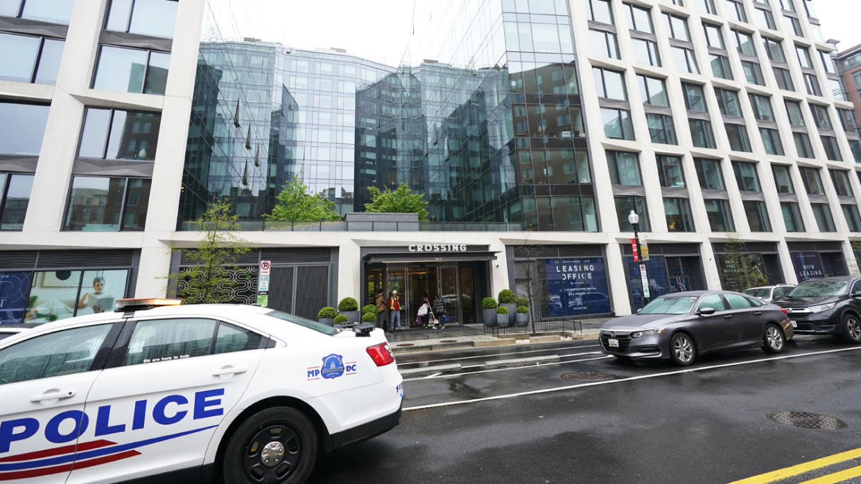 Crossing D.C. apartment building with police car in front.