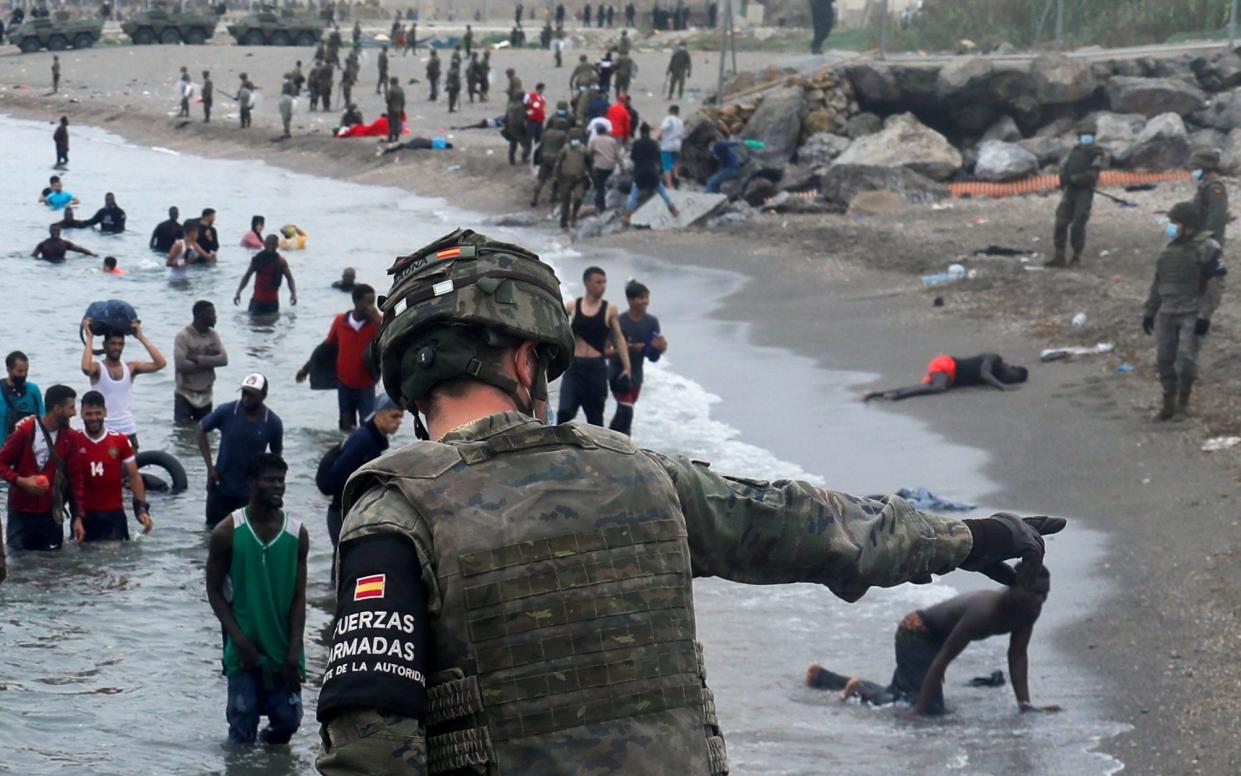 Moroccan migrants swim across the border with Spain on May 18 as a Spanish legionnaire points where they should go.  - Reuters