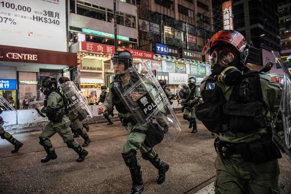 TOPSHOT - Riot police run towards protesters on Nathan road in Hong Kong on December 1, 2019. - Police fired tear gas and pepper spray in Hong Kong on December 1 as tens of thousands of black-clad protesters flooded into the streets, a week after pro-democracy candidates scored a landslide local election victory. (Photo by NICOLAS ASFOURI / AFP) (Photo by NICOLAS ASFOURI/AFP via Getty Images)