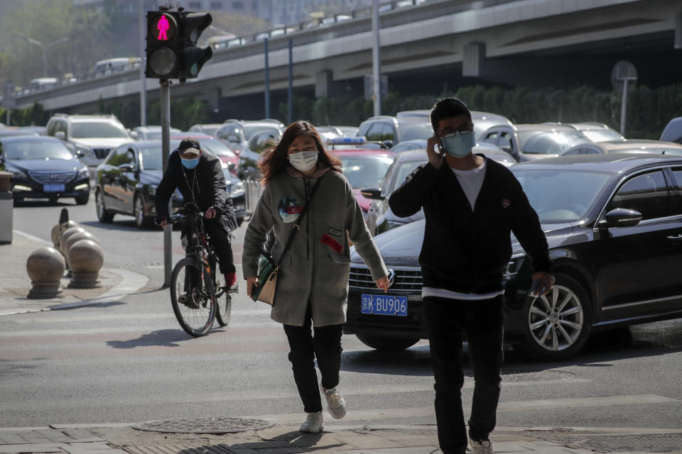 Pictured is a street crossing in Beijing with two pedestrians wearing masks as is a passing cyclist