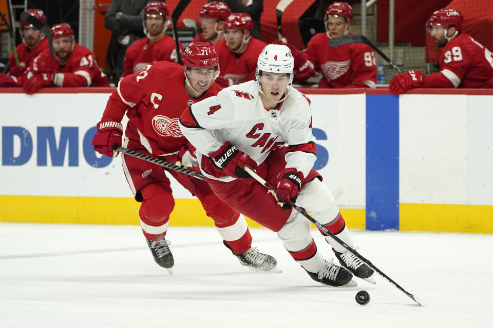 Carolina Hurricanes defenseman Haydn Fleury (4) protects the puck from Detroit Red Wings center Dylan Larkin (71) in the second period of an NHL hockey game Sunday, March 14, 2021, in Detroit. (AP Photo/Paul Sancya)