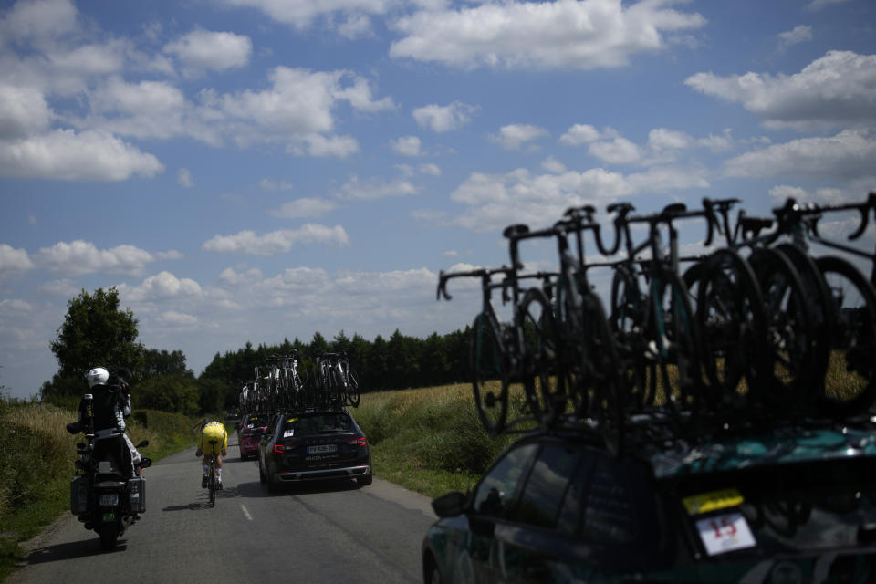 Belgium's Wout Van Aert, wearing the overall leader's yellow jersey rides past sport directors cars during the fourth stage of the Tour de France cycling race over 171.5 kilometers (106.6 miles) with start in Dunkerque and finish in Calais, France, Tuesday, July 5, 2022. (AP Photo/Daniel Cole )