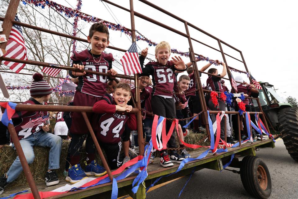 Youth football players wave American flags on a patriotic float during the Tri-Town Veterans Day Parade for West Bridgewater, East Bridgewater and Bridgewater in West Bridgewater, on Veterans Day, Friday, Nov. 11, 2022.