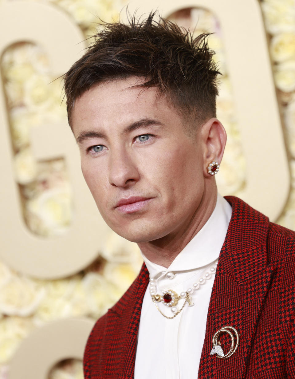 Man in red checkered suit jacket with white shirt, brooch, and circular earrings