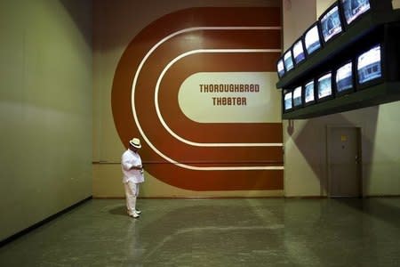 A race-goer checks his phone under a bank of televisions showing horse races for bettors before the 138th running of the Preakness Stakes at Pimlico Race Course in Baltimore, Maryland, May 18, 2013. REUTERS/Jonathan Ernst/Files