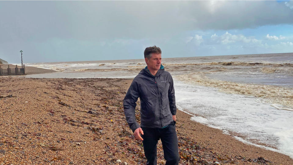 Man wearing Klättermusen Ansur hooded windproof jacket on beach