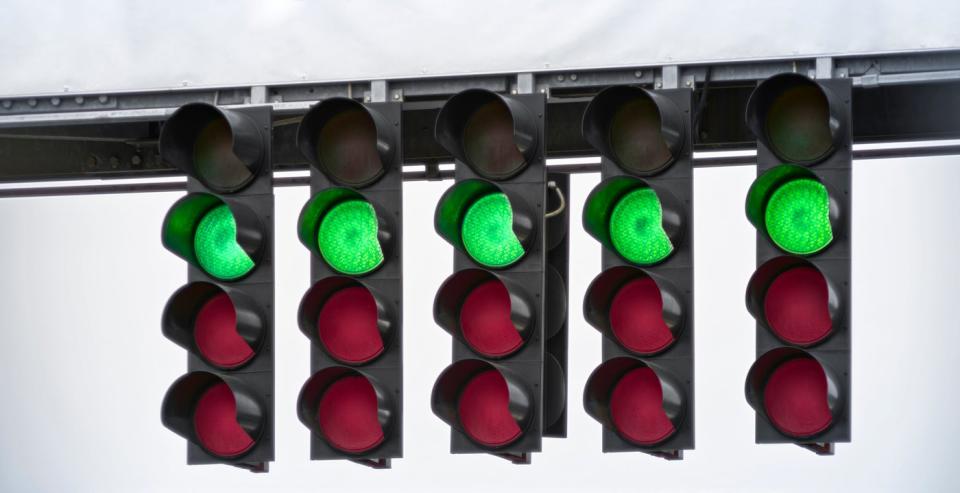 A set of five traffic lights with the green lights illuminated.