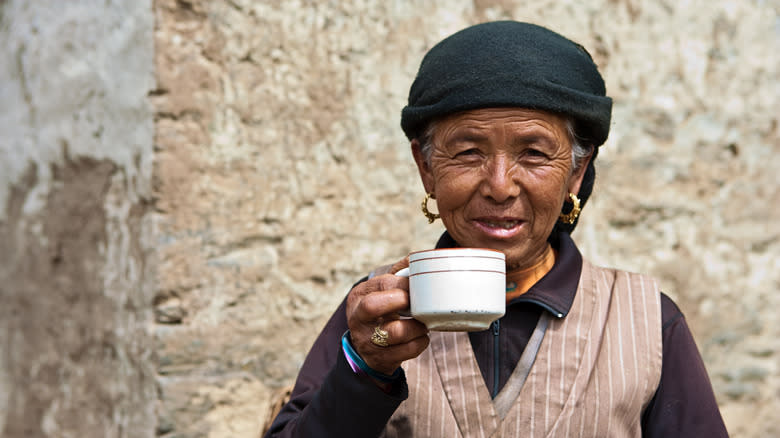 Nepalese woman holding up cup